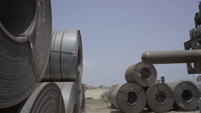 Heavy duty forklift stacks rolled steel coil in sea port shipping yard