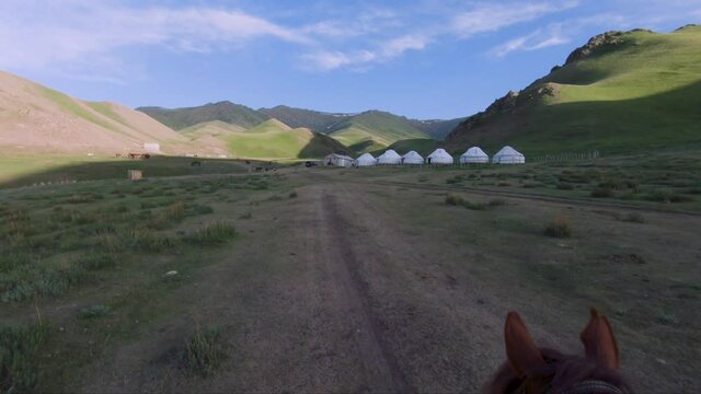 Beautiful Mongol nomads camp, Mongolian steppe with grassland, yurts, horses and car on a blue sjy
