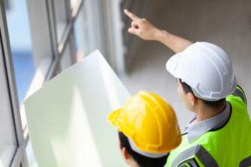 Two engineer looking out the window while discussing over new coming project planning on real estate and infrastructure building in construction industry