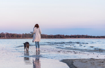 one woman walking with ther dog by the ocean at the beach during sunset 