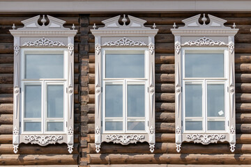 Fragments of architecture - narrow wooden windows with carved platbands on a cobbled house