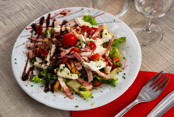 Tourangelle salad with bacon, cherry tomatoes and cheese at plate with balsamic