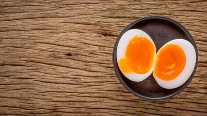 superb runny yolk boiled egg in ceramic plate on rustic natural wood texture background, top view