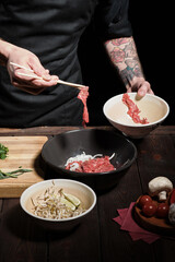 Chef preparing noodle dish with meat