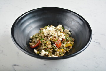 trio quinoa grain salad bowl with avocado, tomato, pea bean, carrot and brown rice in black bowl in white marble healthy poke bowl menu