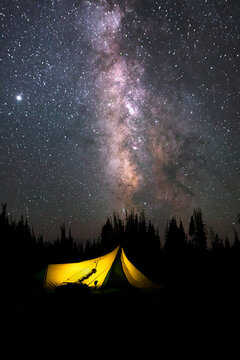A bowhunter's tent is aglow beneath the Milky Way in Wyoming's mountains