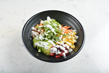 colourful healthy bowl assorted salad, vegetables, avocado, corn, bean, carrot and salad dressing...