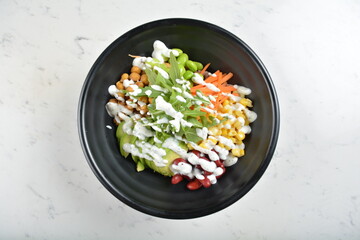 colourful healthy bowl assorted salad, vegetables, avocado, corn, bean, carrot and salad dressing sauce in white marble healthy poke bowl menu
