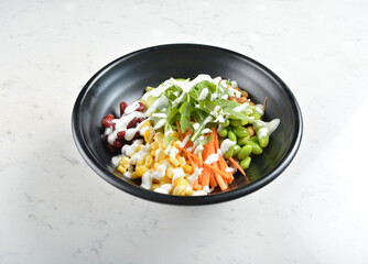colourful healthy bowl assorted salad, vegetables, avocado, corn, bean, carrot and salad dressing sauce in white marble healthy poke bowl menu