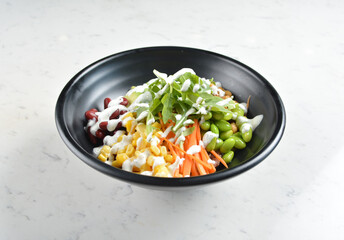 colourful healthy bowl assorted salad, vegetables, avocado, corn, bean, carrot and salad dressing sauce in white marble healthy poke bowl menu