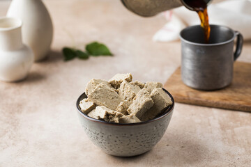 Pieces of halva in bowl and coffee from turka are poured into a mug. Oriental sweetness.