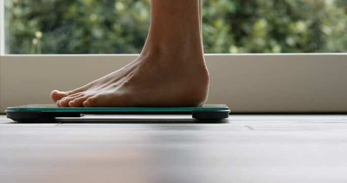 small, thin woman's feet get on and off a bathroom scale