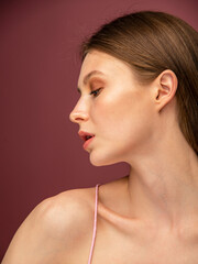 portrait of a woman. Beautiful girl with bare shoulders, on a pink background. Woman with glowing skin