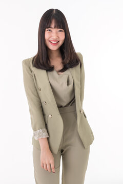 Vertical portrait shot of attractive smiling young Asian woman in formal long sleeve suit sitting at the table while looking at the camera.Young professional female posing in the office workplace