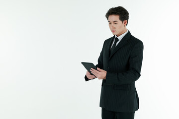 Portrait of self confidence young and handsome business Asian man in black suit holding tablet computer with copy space studio shot isolated on white background