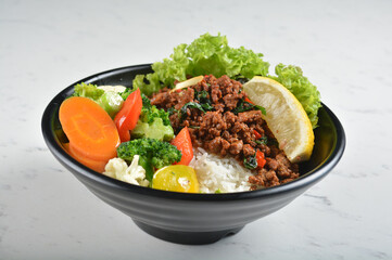 asian spicy thai basil minced pork rice bowl with fried vegetable salad in black bowl in white marble healthy poke bowl menu
