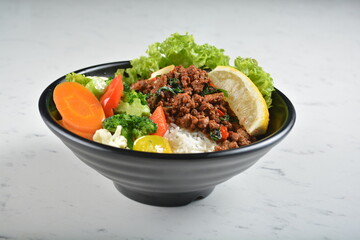 asian spicy thai basil minced pork rice bowl with fried vegetable salad in black bowl in white marble healthy poke bowl menu