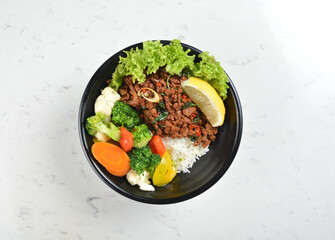 asian spicy thai basil minced pork rice bowl with fried vegetable salad in black bowl in white marble healthy poke bowl menu