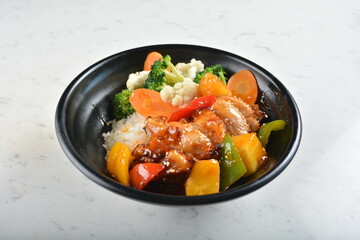 hawaiian sweet & sour grilled chicken pineapple rice bowl with fried vegetable salad in black bowl in white marble healthy poke bowl menu