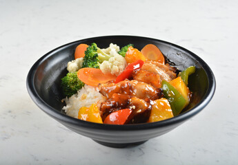 hawaiian sweet & sour grilled chicken pineapple rice bowl with fried vegetable salad in black bowl in white marble healthy poke bowl menu