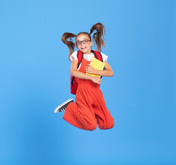 Cheerful schoolgirl with backpack having fin and jumping
