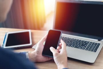 Smart handsome Asian businessman holding a mobile phone. laptop computer tablet to work from home...