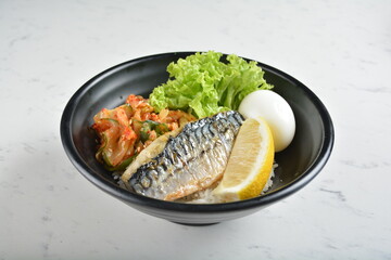 bbq grill korean saba fish seafood with lemon, boiled egg, kimchi and rice bowl in black bowl in...