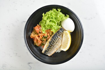 bbq grill korean saba fish seafood with lemon, boiled egg, kimchi and rice bowl in black bowl in...