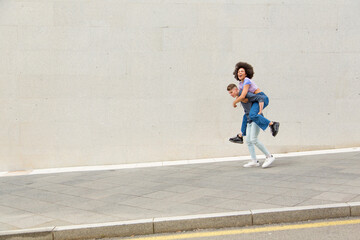 Caucasian young man carrying afro woman on his back smiling
