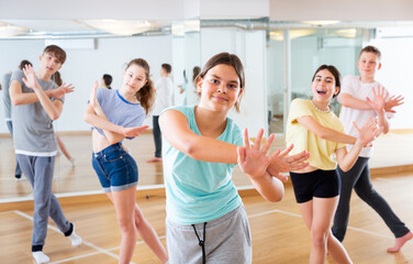 Portrait of emotional teenager girl doing dance workout during group class in studio