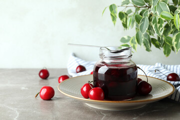 Cherry jam and ingredients on gray textured table