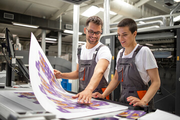 Graphic engineers or workers checking imprint quality in modern print shop. - obrazy, fototapety, plakaty