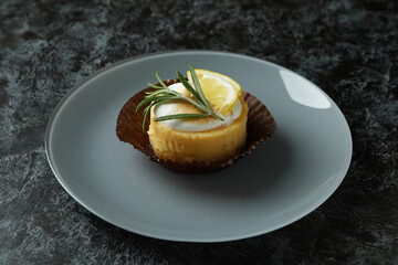 Plate with lemon cupcake on black smokey table