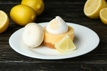 Plate with cupcake and macaroons, and lemons on wooden table