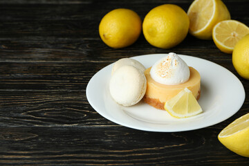 Plate with cupcake and macaroons, and lemons on wooden table
