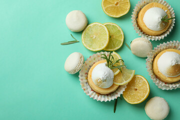Lemon cupcakes, macaroons and ingredients on mint background