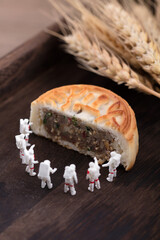 Half a moon cake is surrounded by astronaut dolls to form a full moon