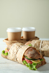 Ciabatta sandwiches and coffee cups on white wooden table