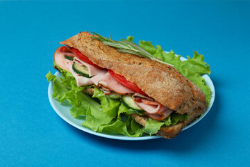 Plate with ciabatta sandwich on blue background
