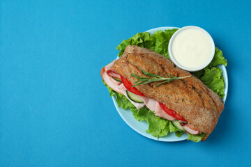 Plate with ciabatta sandwich on blue background