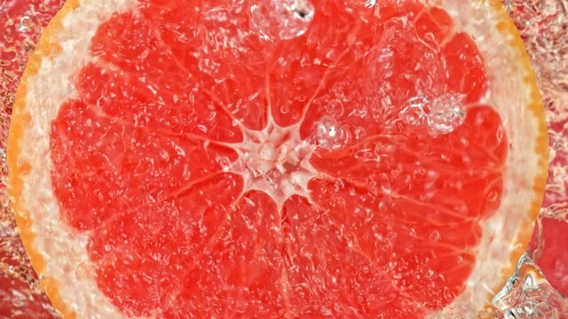 Super Slow Motion Shot of Splashing Water on Rotating Grapefruit Slice at 1000fps.
