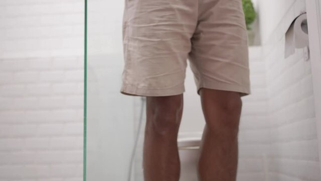 male with stomach ache having a diarrhea standing in toilet and hands hold his belly painfully.