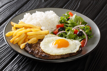 Portuguese dish Bitoque made from beef steak  topped with a fried egg served with rice and french fries, salad closeup in the plate on the table. Horizontal - obrazy, fototapety, plakaty