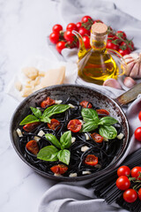 Black spaghetti pasta with tomatoes, cheese and basil