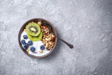 Bowl of healthy breakfast with granola, yogurt, fresh fruits, berries and nuts