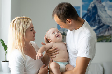 middle-aged parents with baby in white bedroom
