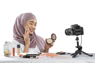 Asian muslim woman beauty blogger tutorial by puff powder makeup on cheek and making videos to review cosmetic products to share on website or social media