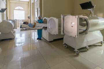 Man and nurse at a hyperbaric treatment machine in a clinic