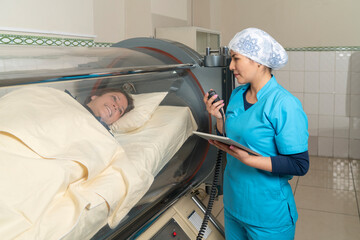 Nurse talking with a patient in a tank of an hyperbaric machine