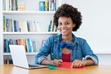 Pretty african american female student learning at desk indoors at library